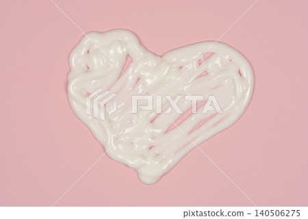 White cosmetic cream smudge shaped as a heart on pink background White cosmetic cream smudge shaped as a heart on pink background 140506275
