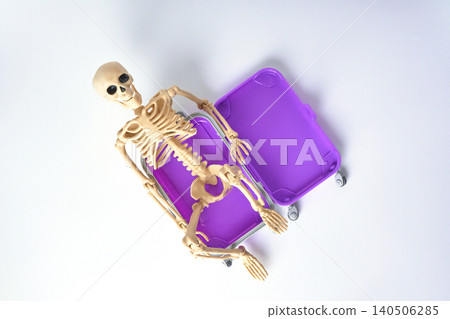 Top view of a Playful Skeleton Relaxing Inside a Bright Purple Suitcase on a White Background Top view of a Playful Skeleton Relaxing Inside a Bright Purple Suitcase on a White Background 140506285