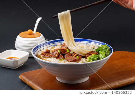 Lifting Noodles with Chopsticks from a Bowl of Chinese Braised Beef Soup. Hot Asian Ramen, Food Action Shot. 140506333