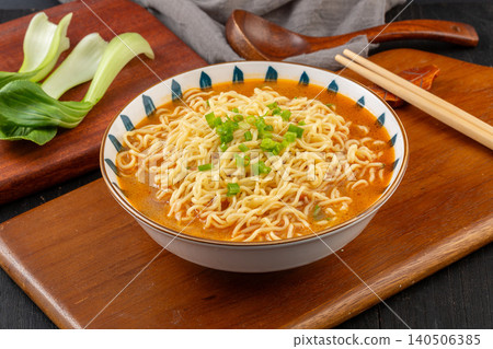 Bowl of Instant Noodles in Savory Broth Topped with Fresh Scallions. Quick Asian Ramen Soup, Comfort Food on Black Background. 140506385