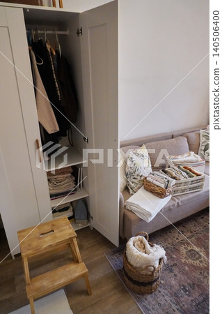 Organized Living Space Featuring a Wardrobe, Couch and Neatly Folded Blankets for Coziness Organized Living Space Featuring a Wardrobe, Couch and Neatly Folded Blankets for Coziness 140506400