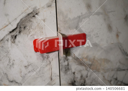 A Close-Up View of a Unique Red Handle on a Sealed Marble Cabinet Door with Natural Patterns A Close-Up View of a Unique Red Handle on a Sealed Marble Cabinet Door with Natural Patterns 140506681
