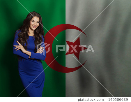 Successful young woman in blue dress smiling against flag of Algeria background 140506689