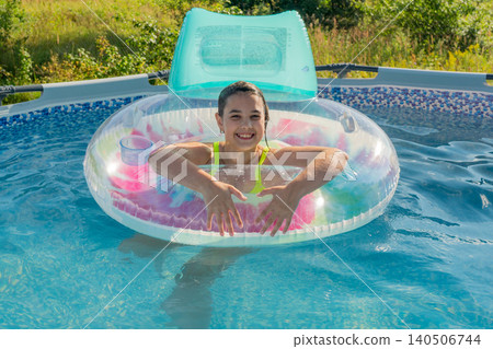 Happy hispanic girl enjoying summer in inflatable pool float Happy hispanic girl enjoying summer in inflatable pool float 140506744