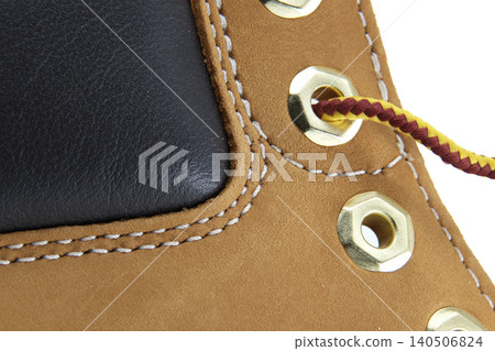 Close-up of tan nubuck leather boot with black panel and brass eyelets Close-up of tan nubuck leather boot with black panel and brass eyelets 140506824