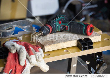 Cordless drill and safety gear ready for woodworking project on workbench Cordless drill and safety gear ready for woodworking project on workbench 140506830