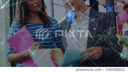 Reviewing duo reading color wheel brochure and pink folder in office with network overlay in blazer 140506921