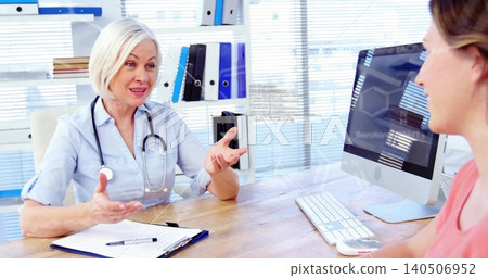 Speaking doctor in blue shirt gesturing toward patient at desk, pink top, stethoscope, copy space Speaking doctor in blue shirt gesturing toward patient at desk, pink top, stethoscope, copy space 140506952