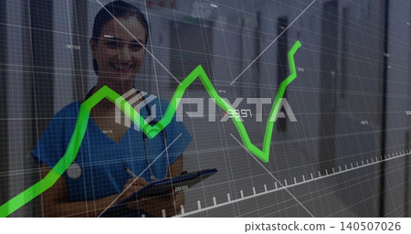Writing notes, Indian nurse in blue scrubs with clipboard under green overlay, ward, copy space 140507026