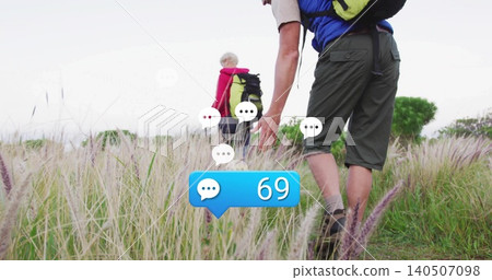 Walking hikers in tall field, with green pack, red-jacketed and blue-top, 69 bubble, copy space Walking hikers in tall field, with green pack, red-jacketed and blue-top, 69 bubble, copy space 140507098