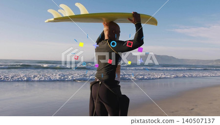 Mature man in dark wetsuit holding yellow surfboard overhead at wet sand with surf leash, overlays Mature man in dark wetsuit holding yellow surfboard overhead at wet sand with surf leash, overlays 140507137