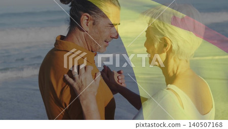 Embracing gray-haired couple man brown shirt woman white top at shoreline with rings umbrella bands 140507168