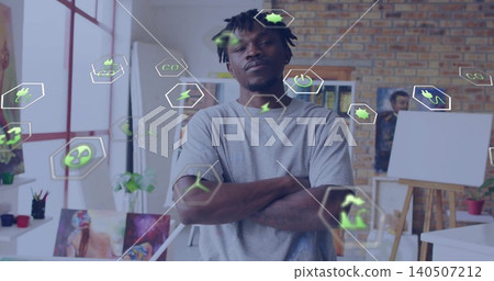 Standing man wearing grey tee, looking toward camera in art studio, easels and green energy icons Standing man wearing grey tee, looking toward camera in art studio, easels and green energy icons 140507212