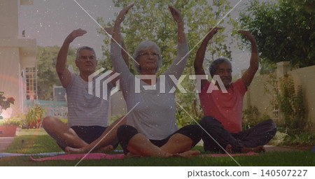 Practicing three seniors stretching arms overhead in home garden, wearing light tops with yoga mats Practicing three seniors stretching arms overhead in home garden, wearing light tops with yoga mats 140507227