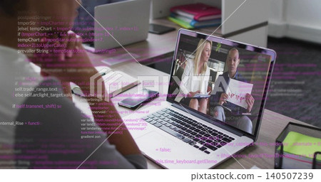 Displaying laptop screen showing remote meeting at office desk, with printed charts, blazer 140507239
