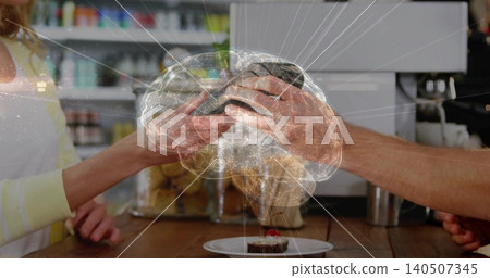 Handing woman wearing pale yellow sweater exchanging payment device at cafe counter, brain overlay Handing woman wearing pale yellow sweater exchanging payment device at cafe counter, brain overlay 140507345