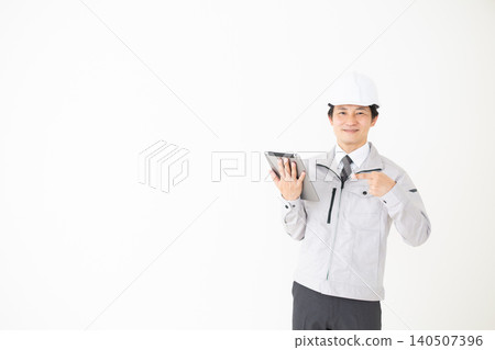 一位身穿灰色工作服的中年商人指著白色背景上的平板電腦。 一位身穿灰色工作服的中年商人指著白色背景上的平板電腦。 140507396