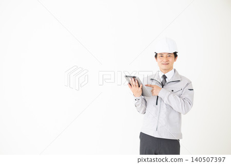 一位身穿灰色工作服的中年商人指著白色背景上的平板電腦。 一位身穿灰色工作服的中年商人指著白色背景上的平板電腦。 140507397