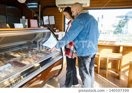 Young man and woman choosing ice cream together at a cafe Young man and woman choosing ice cream together at a cafe 140507399