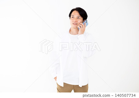 一位身穿白襯衫的中年男子在白色背景前使用智慧型手機通話。 140507734