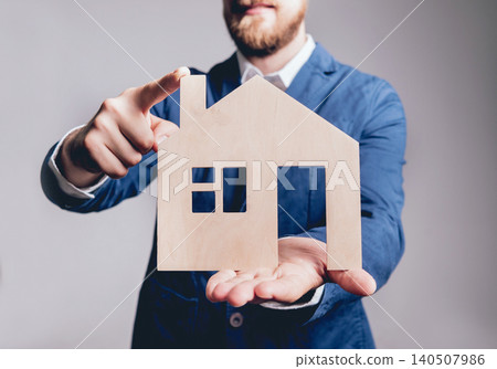 Man proposing signing a estate insurance policy, the agent is holding the wooden house model. Estate insurance concept. Man proposing signing a estate insurance policy, the agent is holding the wooden house model. Estate insurance concept. 140507986