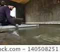 Construction worker carefully screeding wet concrete, leveling a new subfloor during building renovation, creating a smooth surface for future finishing work. 140508251