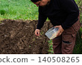 Man planting seeds by hand in freshly tilled garden soil, cultivating new life and demonstrating a commitment to agriculture, natural growth, and self-sufficiency 140508265