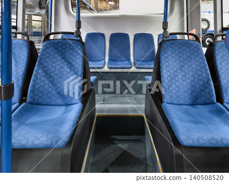 Interior of a city bus showing empty blue seats and a clean environment in a transportation setting during the day 140508520