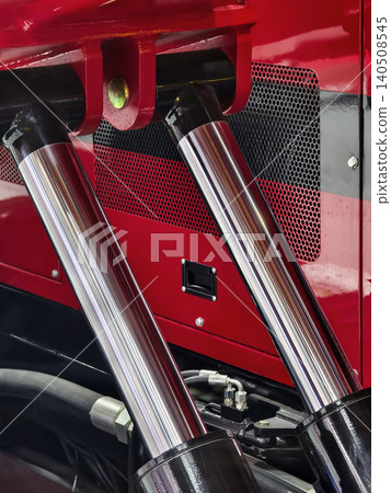 Close view of truck components showing hydraulic cylinders and engine details in a garage during daytime work Close view of truck components showing hydraulic cylinders and engine details in a garage during daytime work 140508545