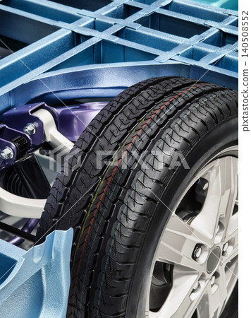 Close view of a car tire mounted on a wheel showing the vehicle's frame and suspension system Close view of a car tire mounted on a wheel showing the vehicle's frame and suspension system 140508552