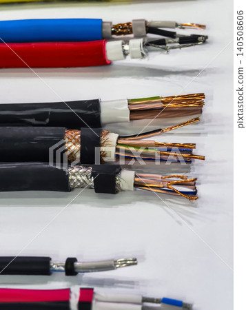 Different types of electrical wires and cables arranged on a white surface for inspection and analysis Different types of electrical wires and cables arranged on a white surface for inspection and analysis 140508606