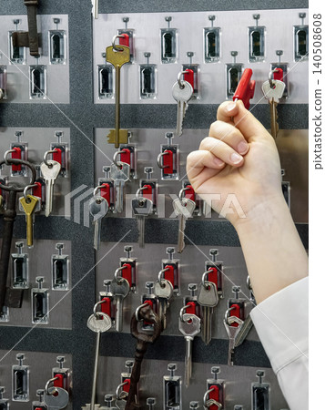 Choosing a key from a wall display of various keys and key holders in a storage area or office setting Choosing a key from a wall display of various keys and key holders in a storage area or office setting 140508608