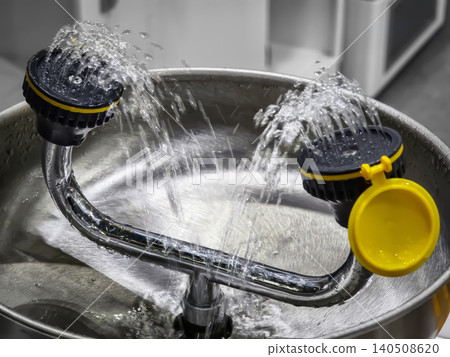 Water flows from two nozzles into a stainless steel basin in a work area during daylight hours Water flows from two nozzles into a stainless steel basin in a work area during daylight hours 140508620