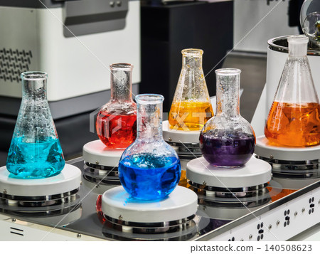 Colorful liquids in glass containers are placed on spinning bases in a laboratory setting during a science demonstration event 140508623