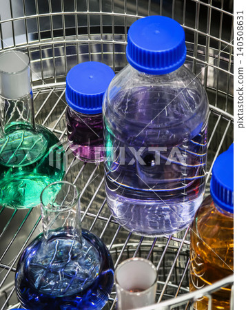 Colorful liquids stored in clear containers on a metal rack in a lab setting during the daytime Colorful liquids stored in clear containers on a metal rack in a lab setting during the daytime 140508631