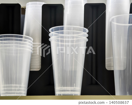 Clear plastic cups are stacked on a shelf in a store ready for use at events or gatherings during the day Clear plastic cups are stacked on a shelf in a store ready for use at events or gatherings during the day 140508637