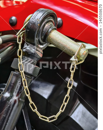 Close view of a metal connector with a chain near a red engine part during an automotive inspection 140508670