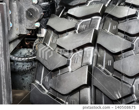 Heavy truck tire showing tread pattern and wheel assembly in a workshop setting during daytime work hours 140508675