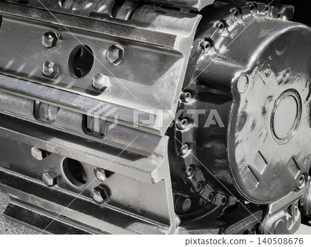 Metal surface shows a close-up of tracks and wheels from heavy equipment in a workshop setting during daytime work hours 140508676