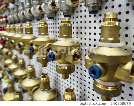 Collection of brass valves displayed on a pegboard in a hardware store during daylight hours 140508679