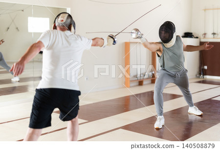 men in protective equipment conduct a training fencing match men in protective equipment conduct a training fencing match 140508879