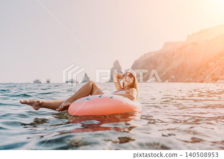 Woman floating sea, enjoying summer vacation on inflatable donut ring in calm ocean waters. Woman floating sea, enjoying summer vacation on inflatable donut ring in calm ocean waters. 140508953