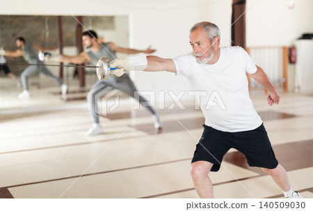 Elderly man attending fencing lessons Elderly man attending fencing lessons 140509030