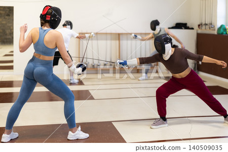 women in protective masks are conducting a fencing training 140509035