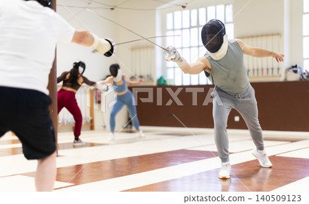 Group of fencers trains in duels and works out blows on the pillows in gym Group of fencers trains in duels and works out blows on the pillows in gym 140509123