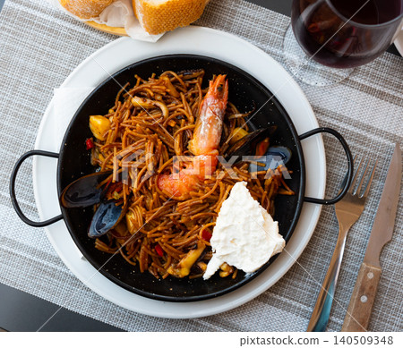 Seafood fideua with shrimps and clams served in paellera with allioli Seafood fideua with shrimps and clams served in paellera with allioli 140509348