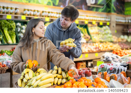 Young couple buying bananas and tangerines in grocery store Young couple buying bananas and tangerines in grocery store 140509423