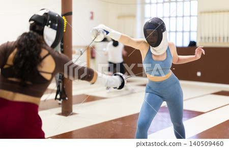 Group of fencers trains in duels and works out blows on the pillows in gym Group of fencers trains in duels and works out blows on the pillows in gym 140509460