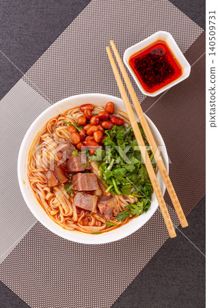 Chinese spicy beef noodle soup served with red chopsticks and chili oil, dark background Chinese spicy beef noodle soup served with red chopsticks and chili oil, dark background 140509731