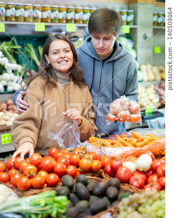 Young woman and young guy choose tomatoes Young woman and young guy choose tomatoes 140509864
